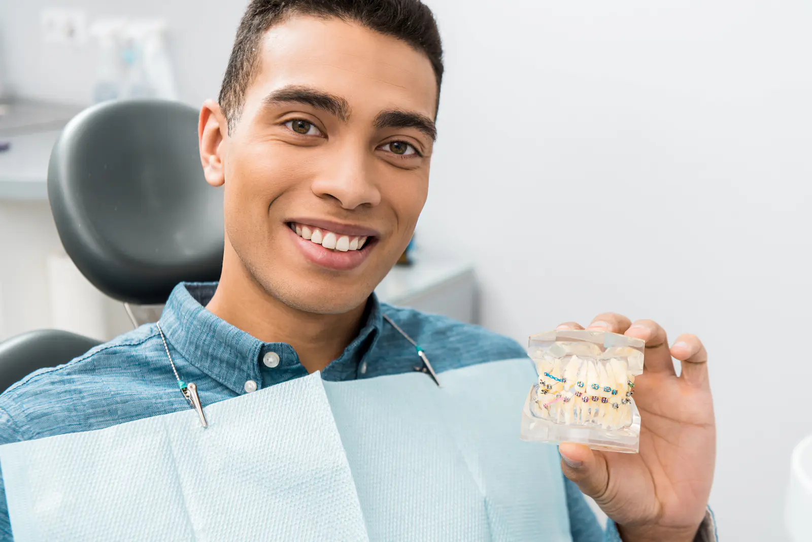 Adult male holding up a model of braces