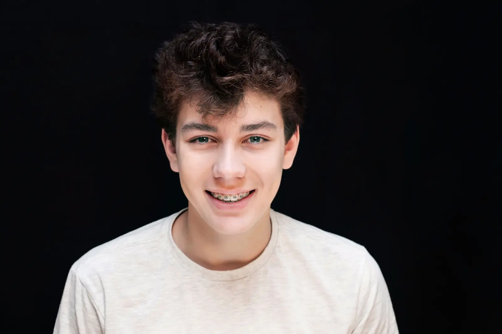 Kid with braces in t-shirt on black background